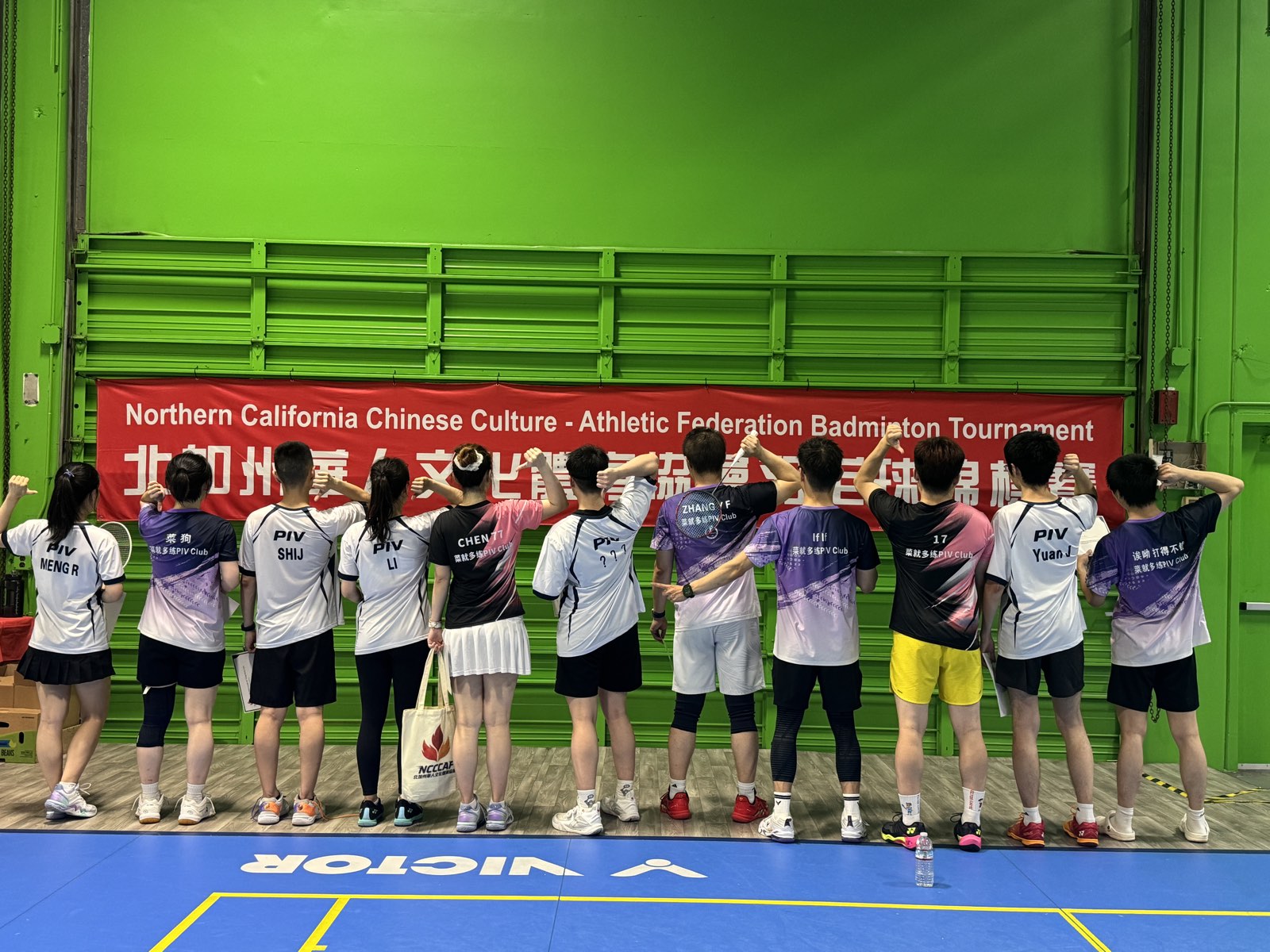 PIV players standing with their backs to the camera, showing the names on their jerseys under the NCCCAF tournament banner